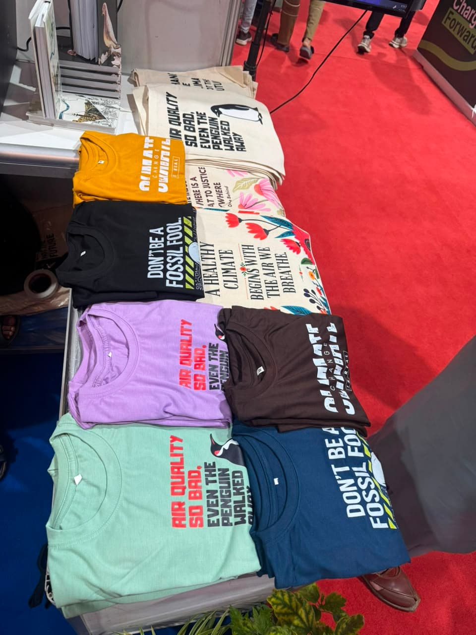 A display table of colourful printed shirts and tote bags