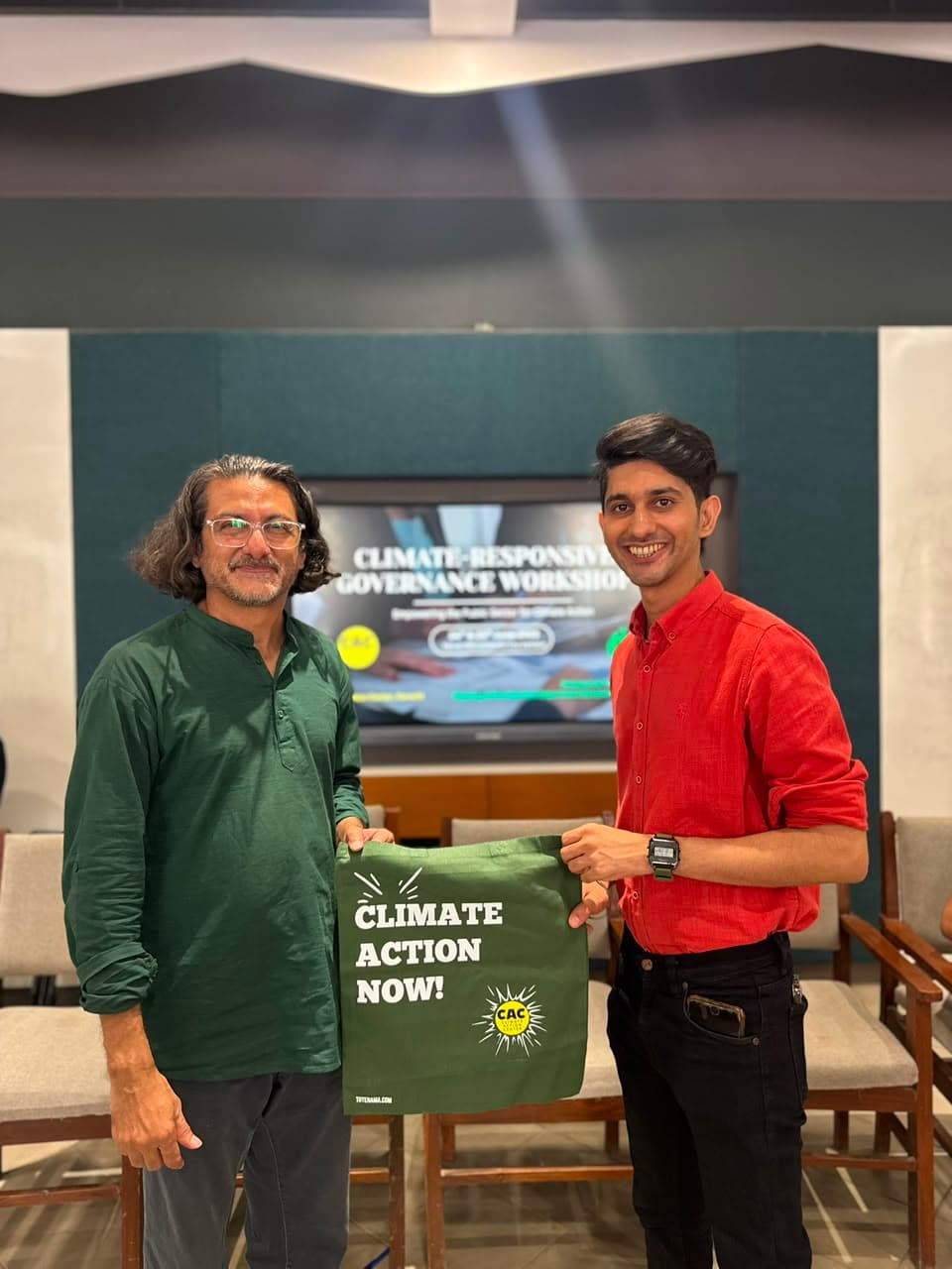 Two men presenting a green Climate Action Now shirt at an event